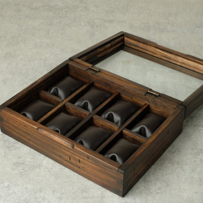A dark brown wooden watch box with a hinged lid and eight individual watch slots lined