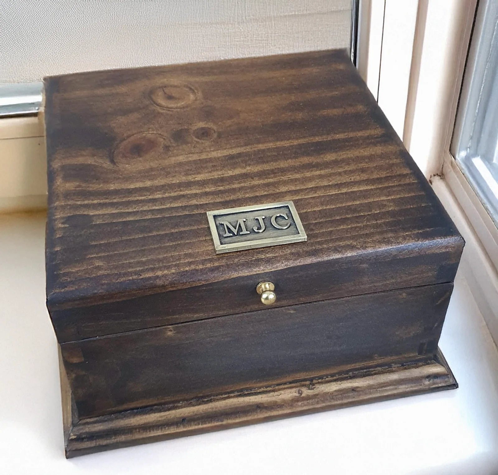 Customer photograph of a compact domed Deferichs wooden box personalized with an MJC nameplate.