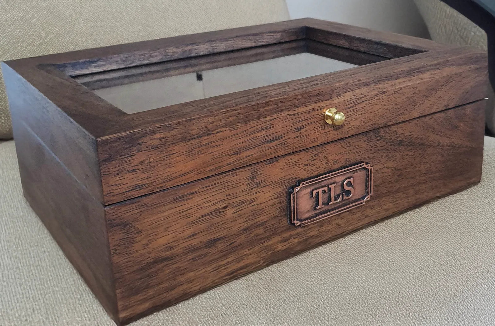 Customer photograph of a glass-lid Deferichs watch box personalized with a TLS copper-finish nameplate.
