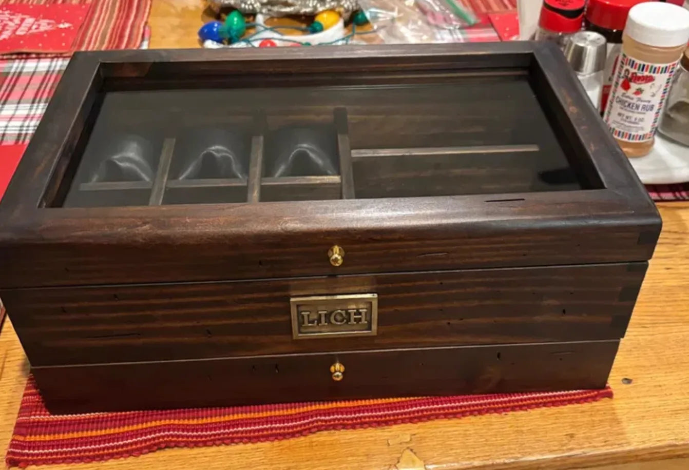 A large personalized Deferichs watch box with glass lid, drawers, and solid brass nameplate.