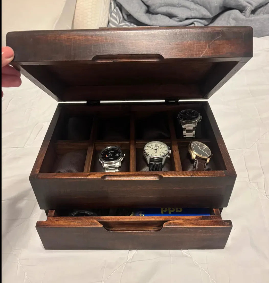 A handcrafted watch box with an open upper compartment and lower drawer in a customer’s home.