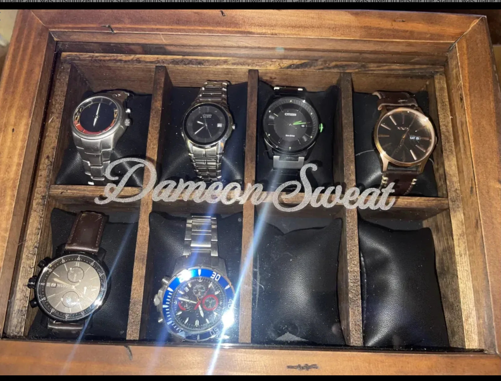A glass-lid wooden watch box personalized across the glass and filled with watches.